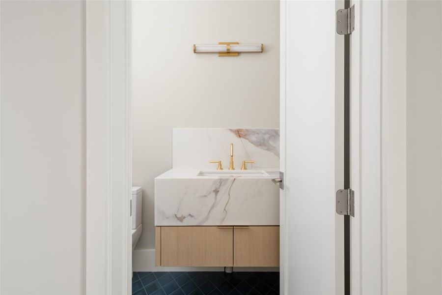 Upstairs powder room with a floating vanity, quartzite surfaces, and warm brass fixtures.