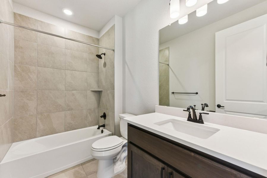 Bathroom featuring bathing tub / shower combination, vanity, light tile patterned flooring, and recessed lighting
