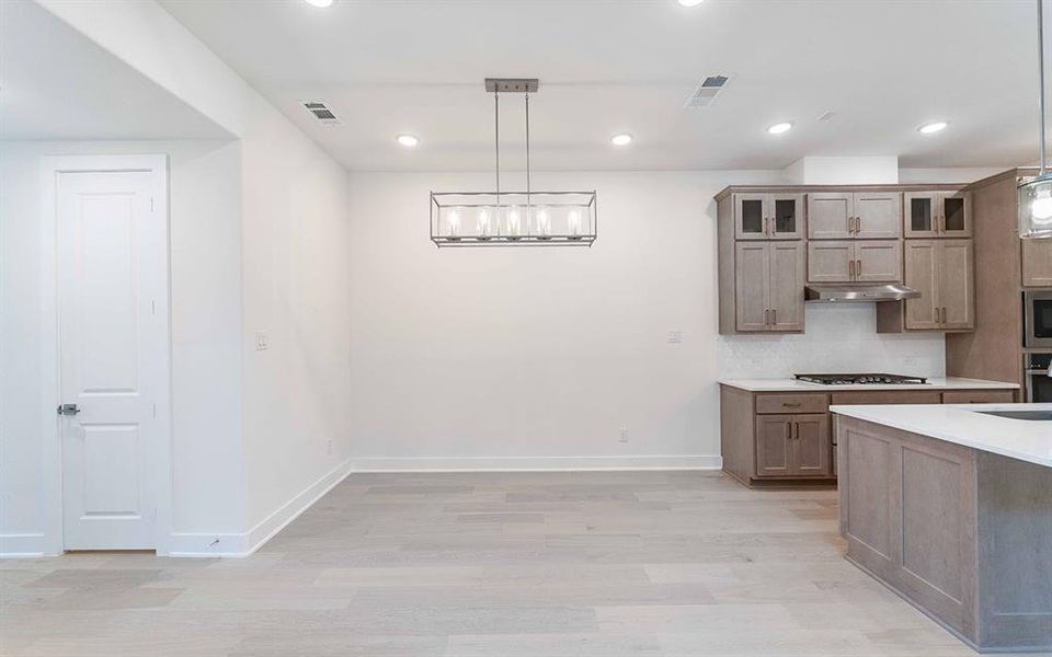 Open-concept living space featuring wood-finish flooring, recessed lighting, and a modern linear chandelier