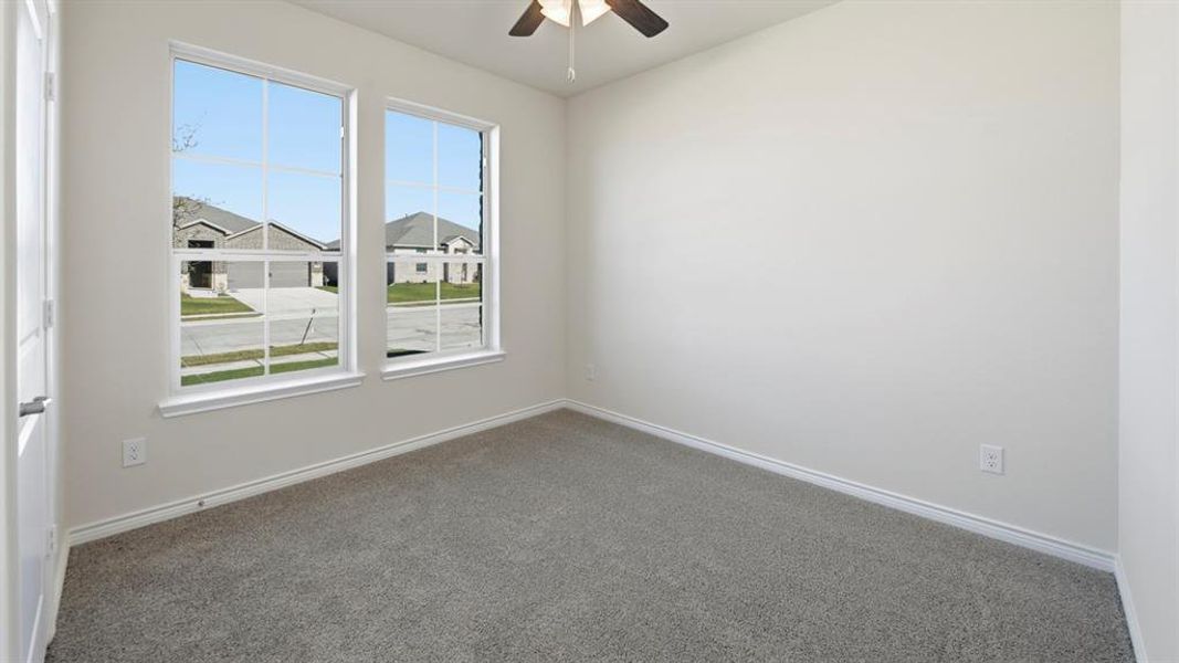 Carpeted empty room featuring ceiling fan and a residential view