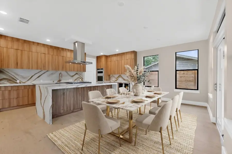 An open concept kitchen and dining space combines rich wood cabinetry with elegant marble finishes.