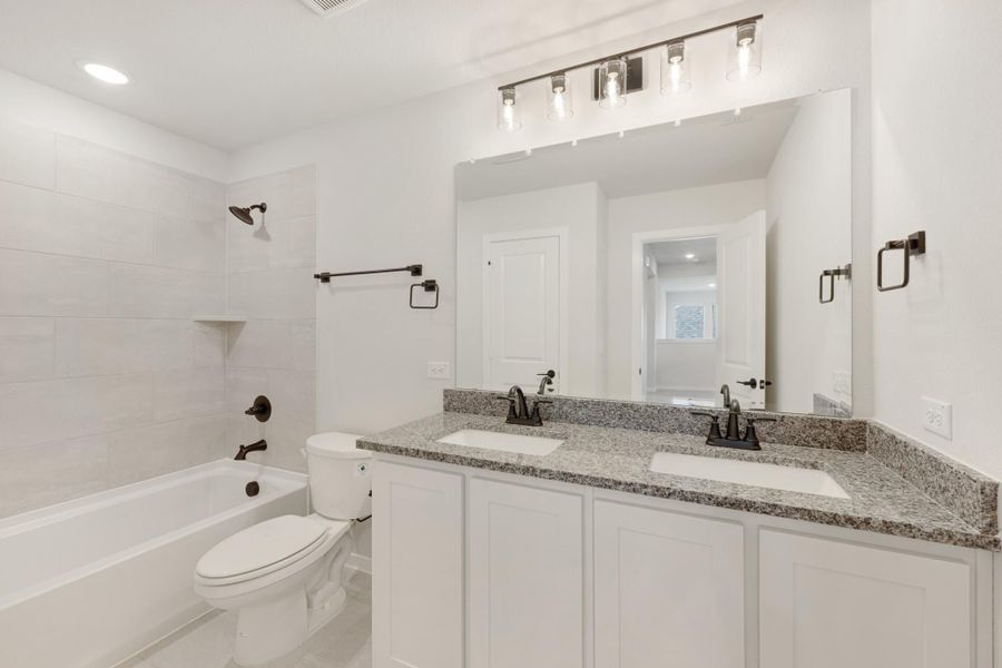 Bathroom with double sink vanity, granite countertop, white cabinets, and tub-shower combo with tile surround Bathroom with double sink vanity, granite countertop, white cabinets, and tub-shower combo with tile surround