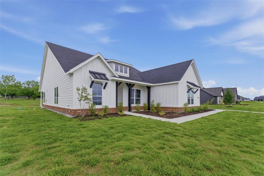 The property features white vertical siding, a dark roof, and a red brick foundation