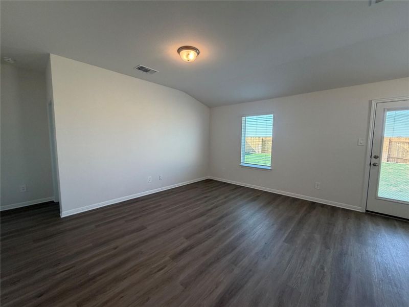 Unfurnished room featuring dark wood-style flooring and lofted ceiling