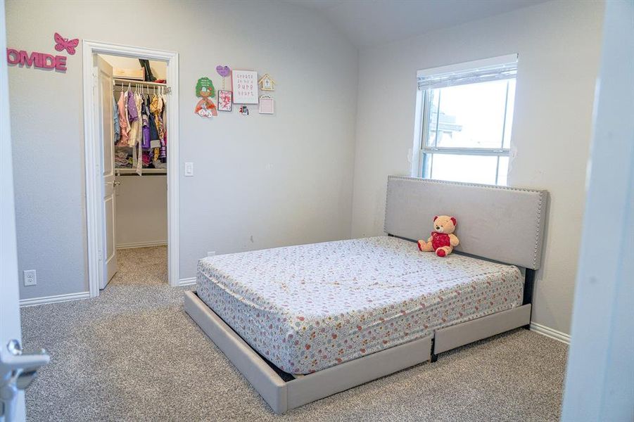 Bedroom featuring light carpet and a walk in closet