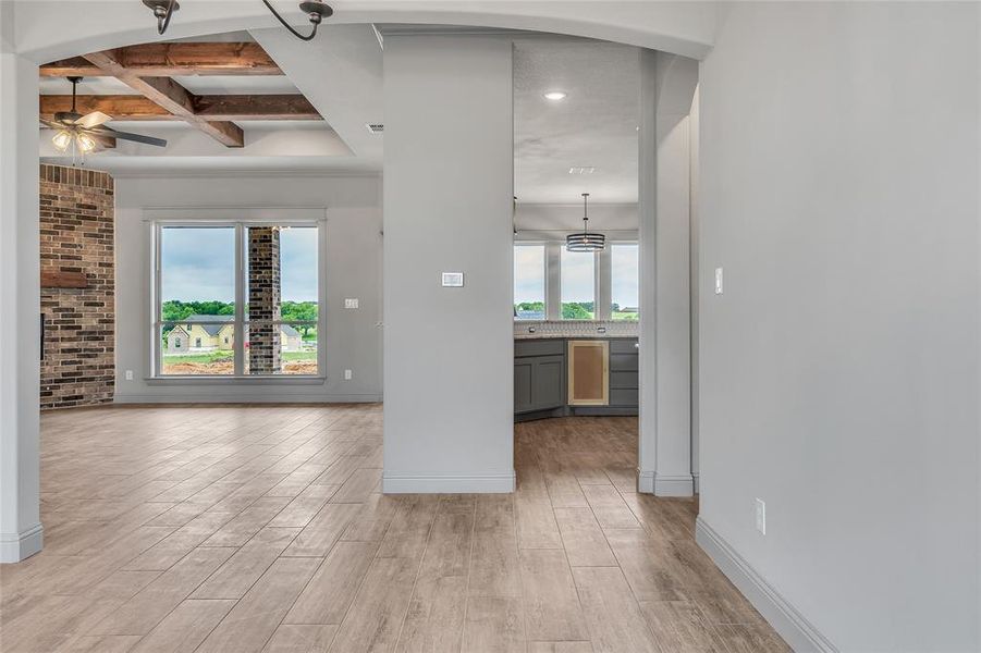 Empty room featuring light hardwood / wood-style flooring, beam ceiling, and ceiling fan