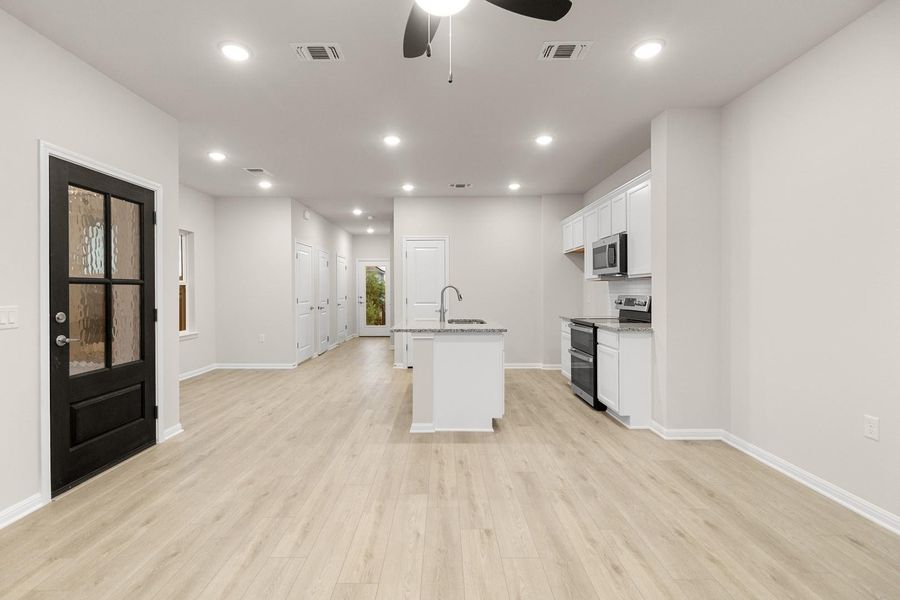 The property features an open living area with light-colored flooring, recessed lighting, and a ceiling fan