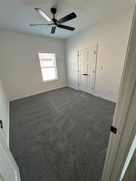 Spare room featuring dark carpet and ceiling fan