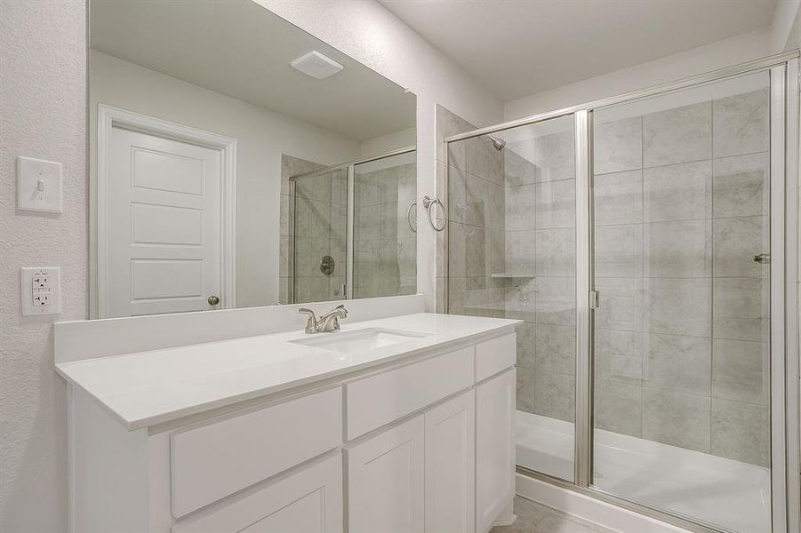 Full bath featuring vanity, a shower stall, and a textured wall