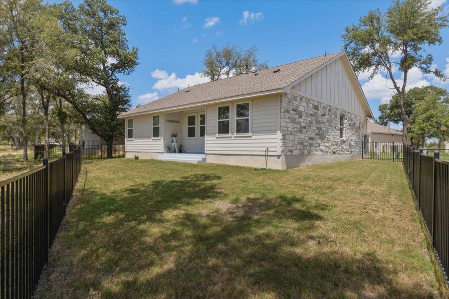 A classic stone and siding exterior defines this home with a fenced backyard lawn.