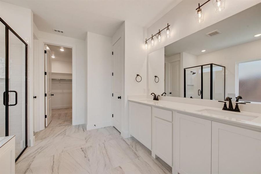 Bathroom featuring a stall shower, double vanity, a walk in closet, light marble finish floors, and recessed lighting Bathroom featuring a stall shower, double vanity, a walk in closet, light marble finish floors, and recessed lighting