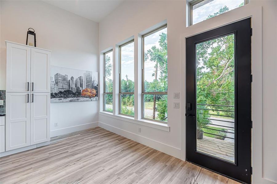 The dining room features a modern design with large windows for natural light, a sleek white storage cabinet, and vinyl wood flooring.