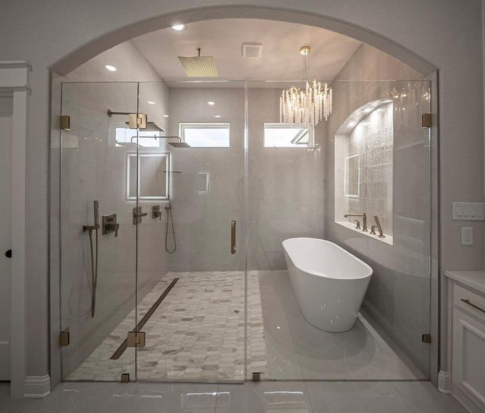 Full bathroom featuring a shower stall, a freestanding tub, light tile patterned floors, a chandelier, and recessed lighting Full bathroom featuring a shower stall, a freestanding tub, light tile patterned floors, a chandelier, and recessed lighting