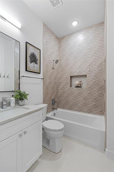 Full bathroom with vanity, tiled shower / bath combo, toilet, and tile patterned floors