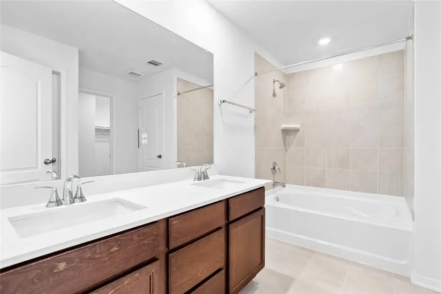 This beautifully updated primary bathroom is move-in ready! It showcases stained cabinetry paired with light countertops, dual vanity sinks, a large mirror, a spacious tub and shower combination with tile surround, high ceilings, custom paint, and stylish modern finishes throughout. This beautifully updated primary bathroom is move-in ready! It showcases stained cabinetry paired with light countertops, dual vanity sinks, a large mirror, a spacious tub and shower combination with tile surround, high ceilings, custom paint, and stylish modern finishes throughout.