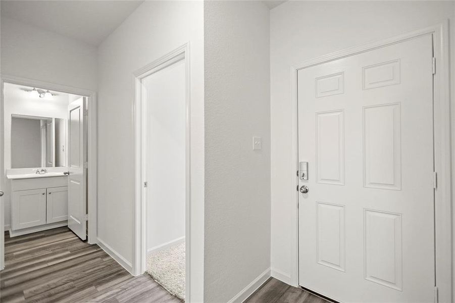 Interior hallway with nearby utility access and direct flow toward secondary bath and bedrooms.