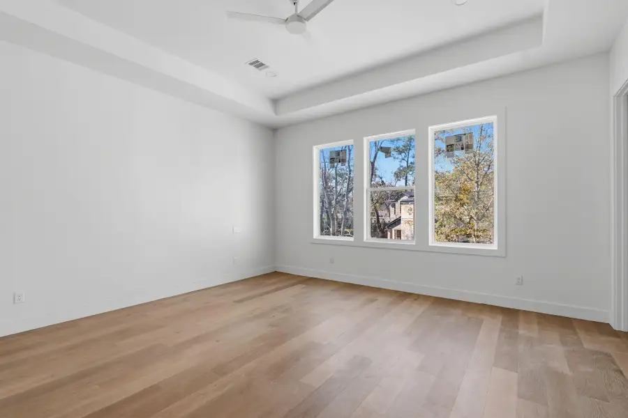 The primary bedroom is positioned to overlook the backyard and is framed by large windows, creating a bright, quiet retreat filled with natural light.