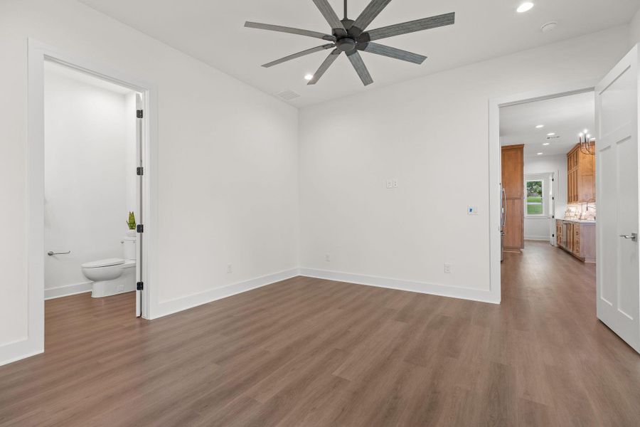 Empty room with a ceiling fan, recessed lighting, wood finished floors, baseboards, and a smoke detector Empty room with a ceiling fan, recessed lighting, wood finished floors, baseboards, and a smoke detector