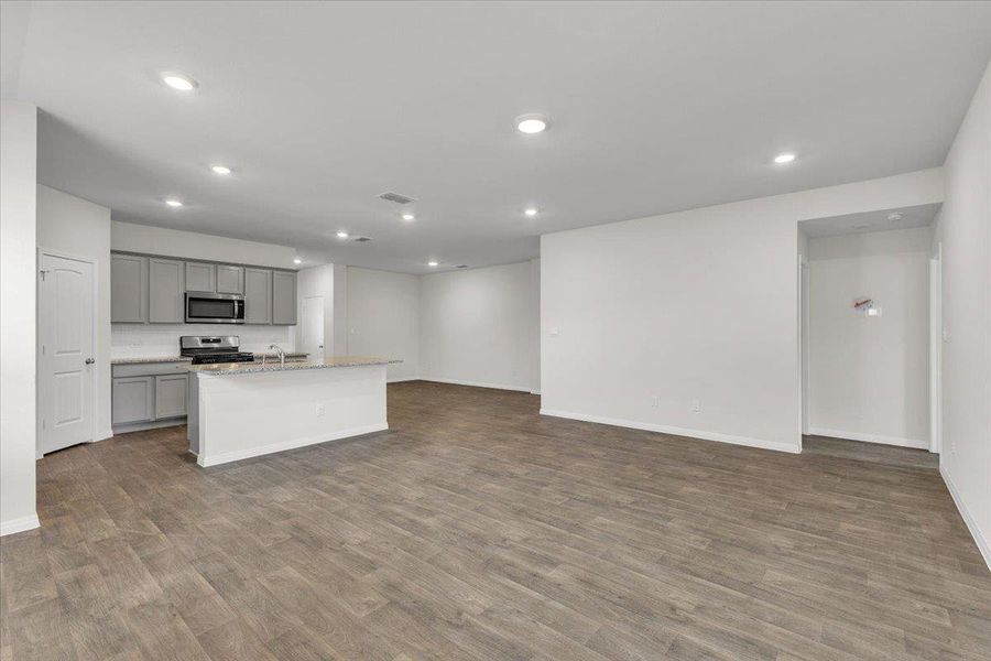 This open-concept living space features light wood-look flooring and recessed lighting throughout