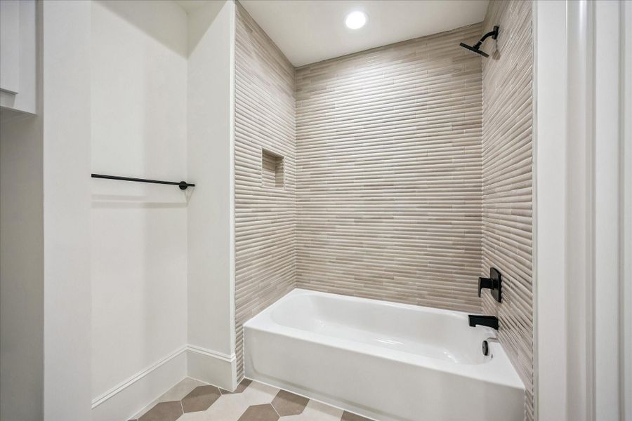 Secondary bath with floor-to-ceiling tile and custom quartz vanities.