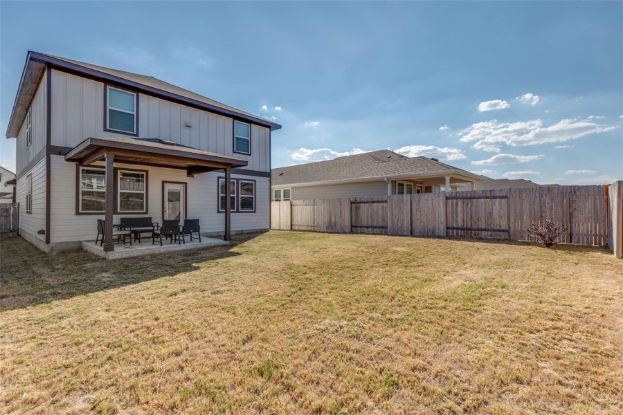 Rear view of property featuring a patio, a fenced backyard, and board and batten siding