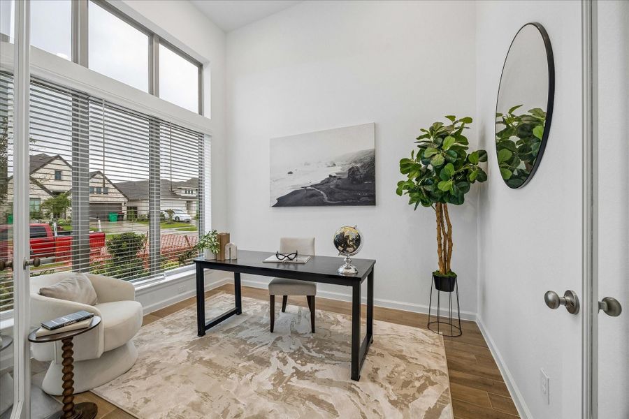 The private home office offers a quiet place to focus with soaring ceilings, stacked windows that bring in natural light, glass French doors for privacy, and beautiful wood-look tile that adds warmth and easy-care style.