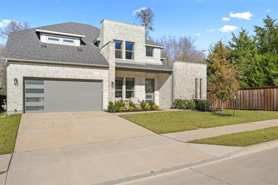 Contemporary home featuring covered porch, roof with shingles, concrete driveway, an attached garage, and brick siding