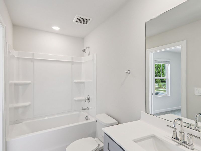 The secondary bathroom features a spacious vanity and oversized shower tub.