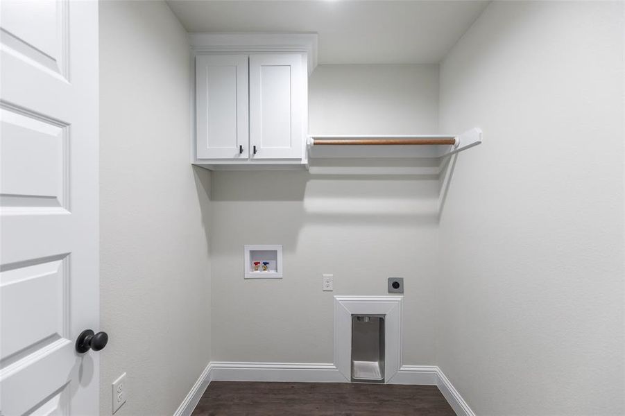 Dedicated laundry area featuring a white shaker-style cabinet, a wood hanging rod, dark wood-finish flooring, and crisp white baseboards