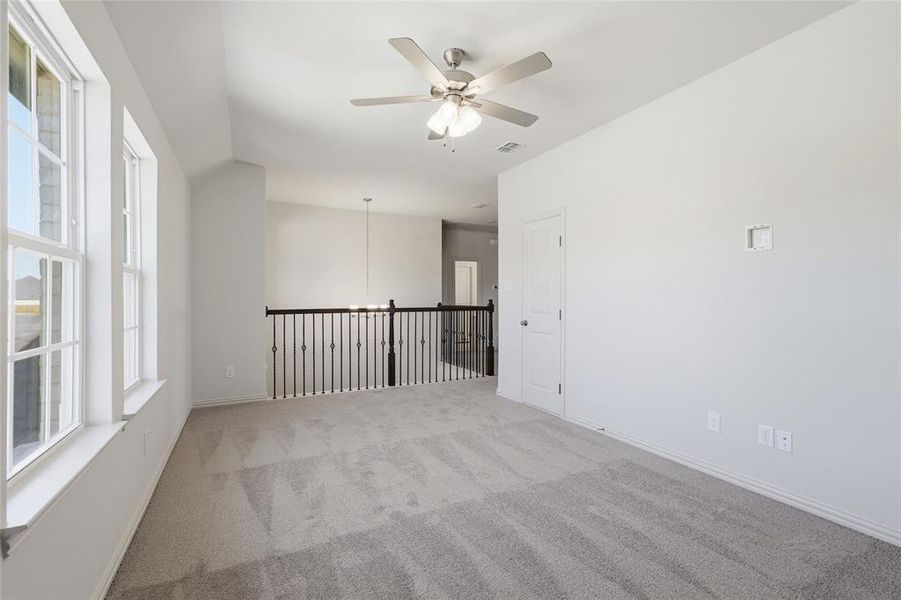 Empty room featuring ceiling fan, light colored carpet, and vaulted ceiling Empty room featuring ceiling fan, light colored carpet, and vaulted ceiling