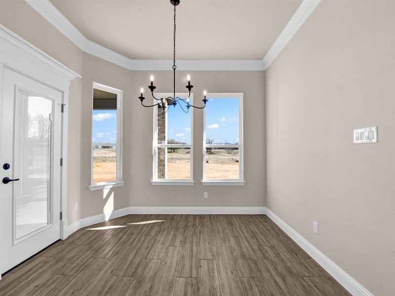 Unfurnished dining area featuring hardwood / wood-style flooring, a notable chandelier, and crown molding