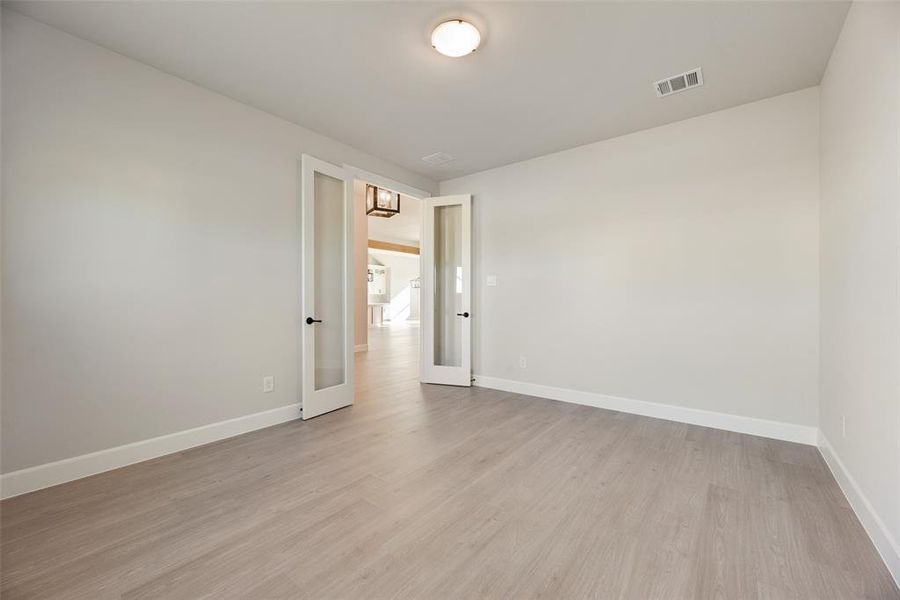 Empty room with light wood-style flooring and french doors Empty room with light wood-style flooring and french doors