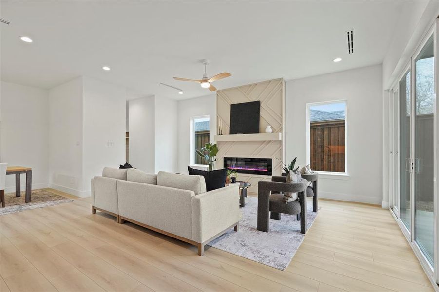 Living room featuring light wood-style flooring, a glass covered fireplace, ceiling fan, and recessed lighting Living room featuring light wood-style flooring, a glass covered fireplace, ceiling fan, and recessed lighting