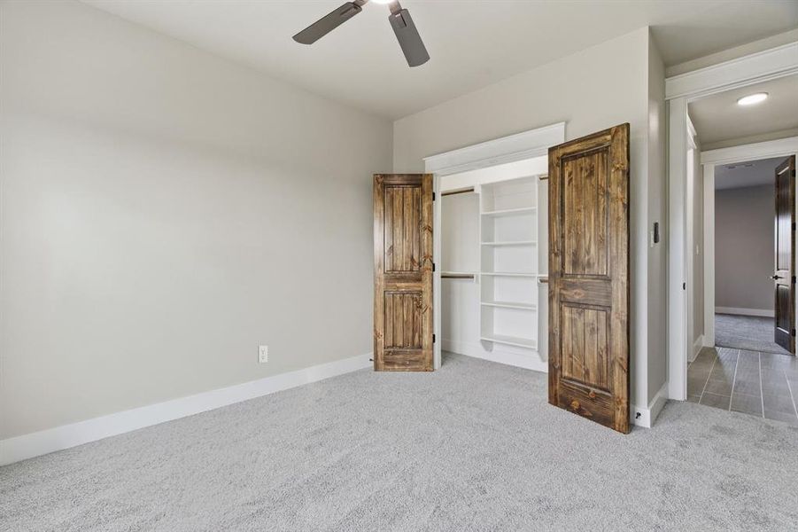 Unfurnished bedroom with light carpet and ceiling fan