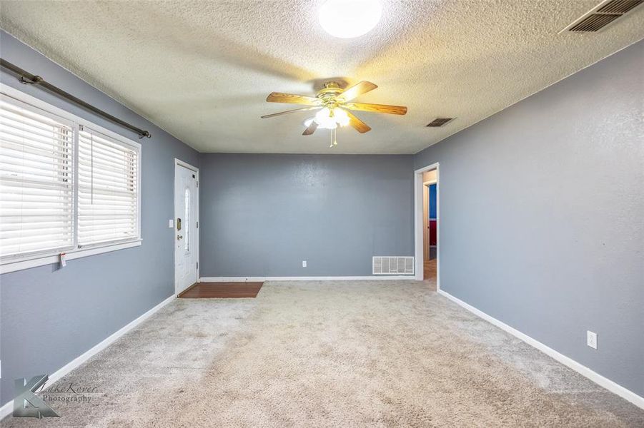 Carpeted spare room featuring a ceiling fan and a textured ceiling