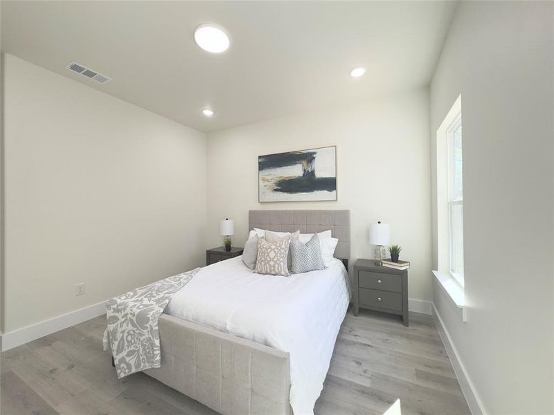 Bedroom with light hardwood / wood-style flooring and multiple windows