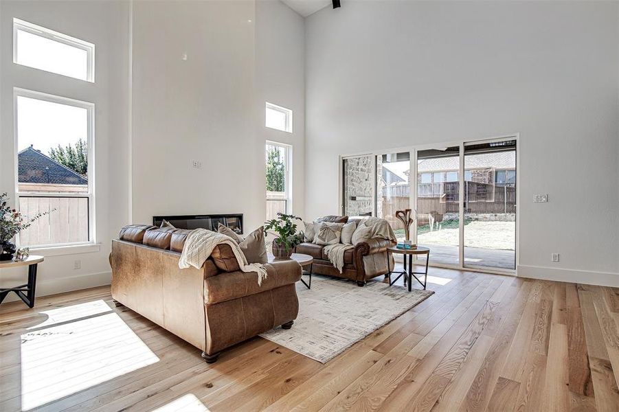 Living room featuring light wood finished floors and a high ceiling. Slide and stack patio doors. Living room featuring light wood finished floors and a high ceiling. Slide and stack patio doors.