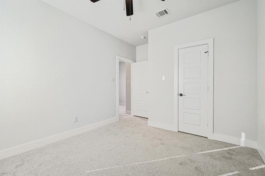 Unfurnished bedroom with light colored carpet and ceiling fan