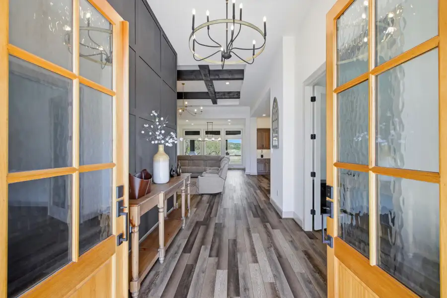 Entryway featuring a decorative chandelier, panel accent wall, and wood-look flooring