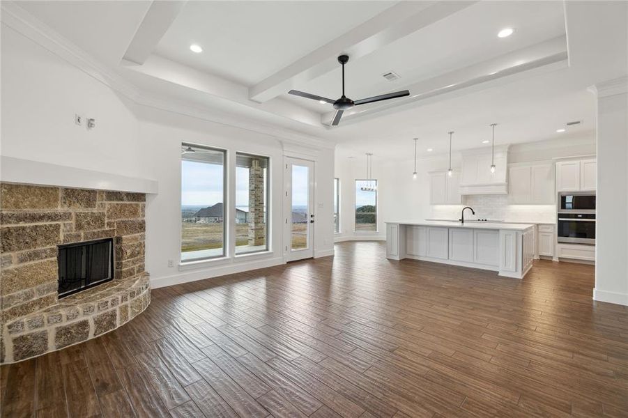 Unfurnished living room with dark hardwood / wood-style flooring, sink, ceiling fan, and a stone fireplace