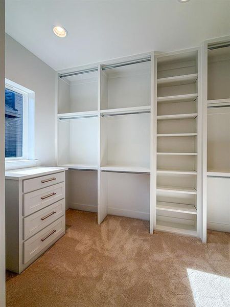 Custom closet system with built-in shelving, hanging rods, and a four-drawer dresser with bronze hardware