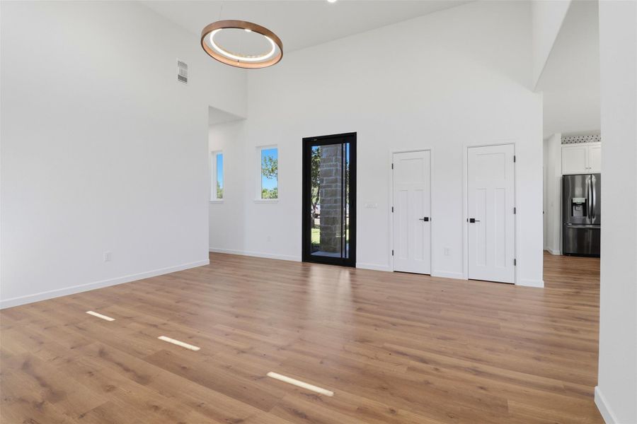 Spacious open-concept room featuring high vaulted ceilings, wood-finish flooring, and crisp white walls Spacious open-concept room featuring high vaulted ceilings, wood-finish flooring, and crisp white walls