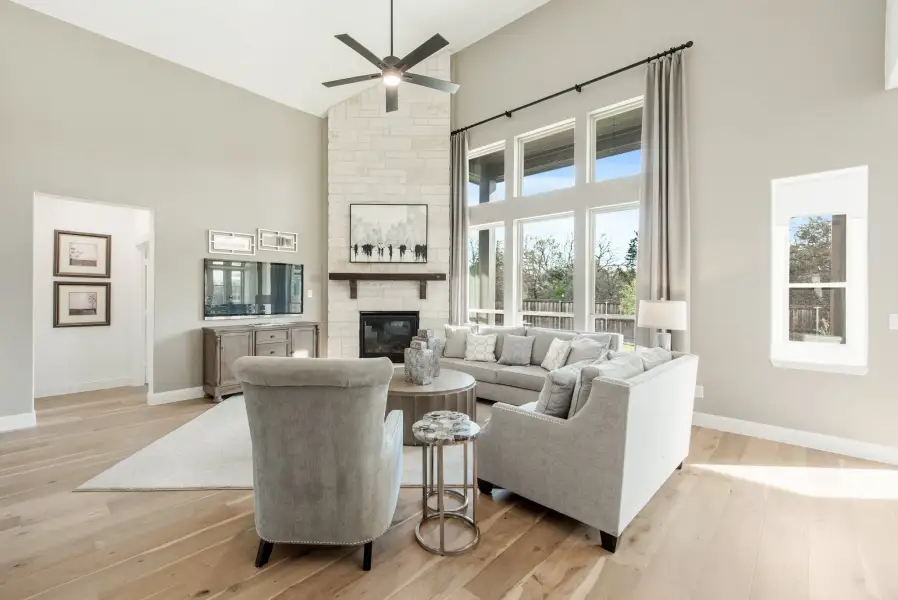 Living room with vaulted ceiling, stone fireplace, gray sectional sofa, and hardwood floors