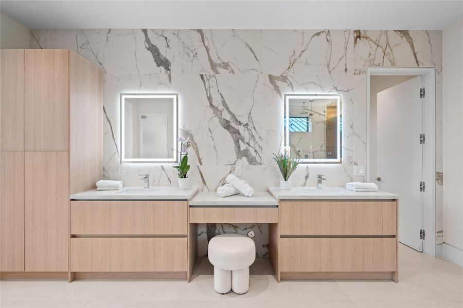 Luxurious dual vanity with LED mirrors and custom cabinetry with built-in makeup station. Luxurious dual vanity with LED mirrors and custom cabinetry with built-in makeup station.