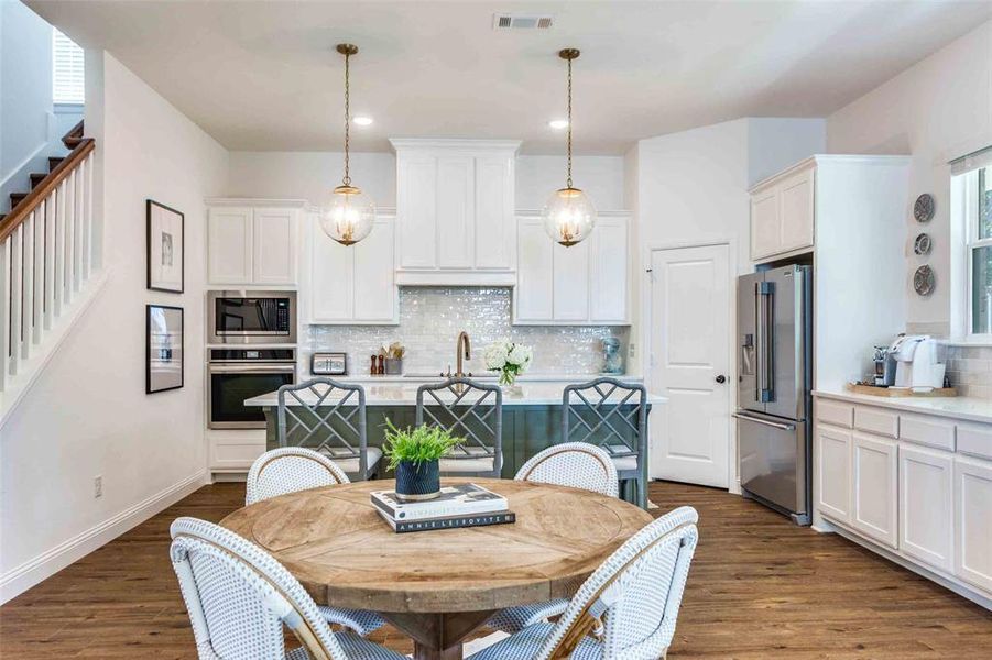 Kitchen with white cabinets, hanging light fixtures, and appliances with stainless steel finishes