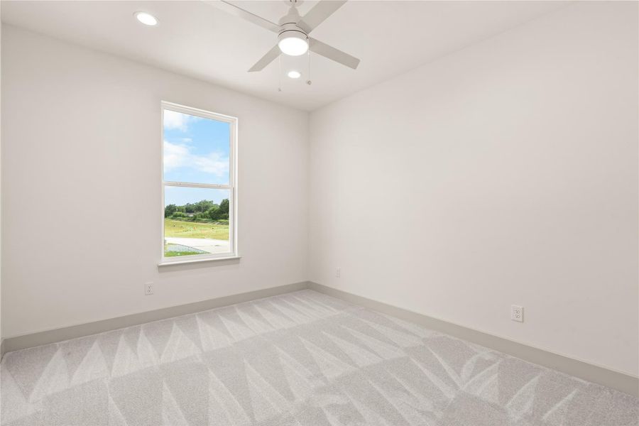 Secondary bedroom — carpet, ceiling fan, and open green views through the window Secondary bedroom — carpet, ceiling fan, and open green views through the window