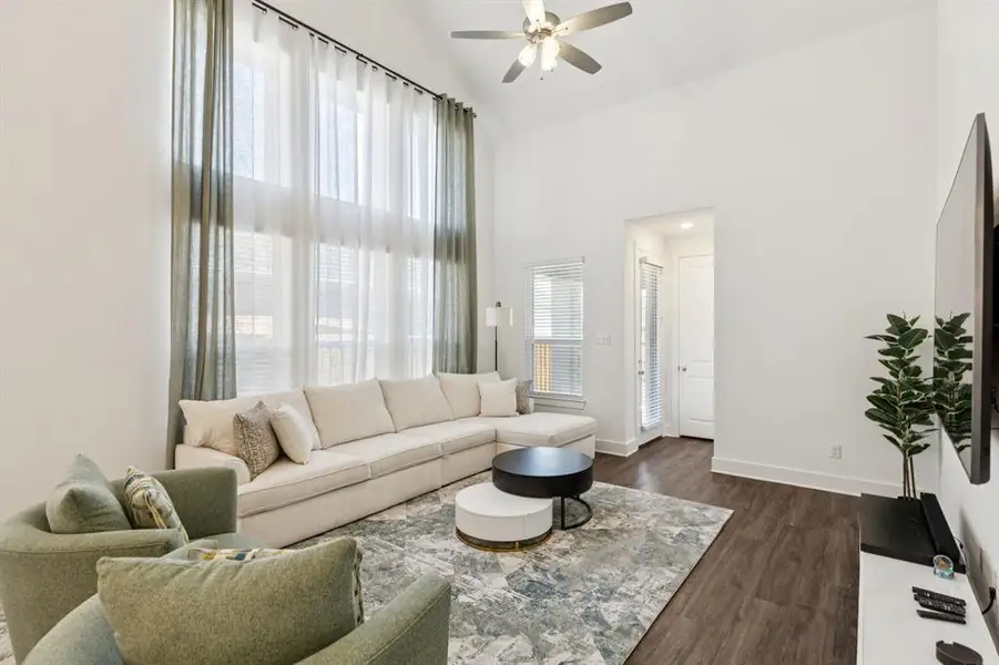 Living area featuring dark wood finished floors, a high ceiling, and ceiling fan Living area featuring dark wood finished floors, a high ceiling, and ceiling fan