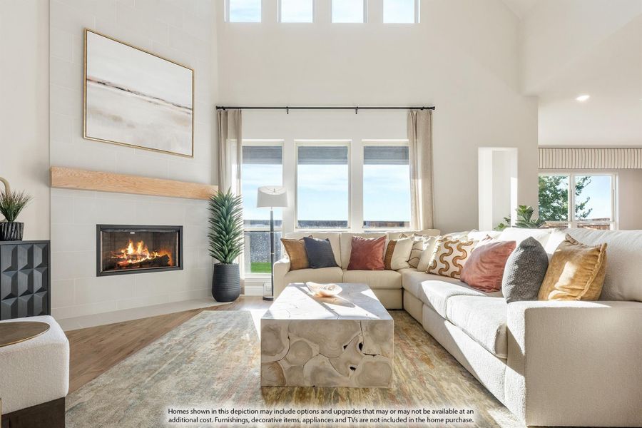 Living room with high ceilings, sectional sofa, fireplace, and large windows letting in natural light Living room with high ceilings, sectional sofa, fireplace, and large windows letting in natural light