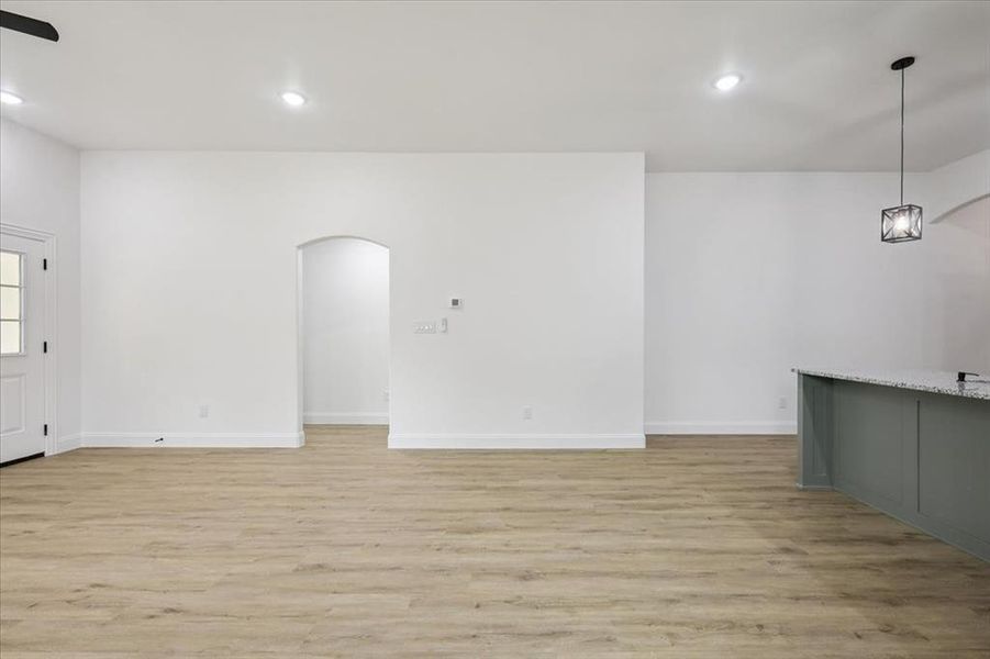 Unfurnished living room with light wood-style floors, recessed lighting, and arched walkways Unfurnished living room with light wood-style floors, recessed lighting, and arched walkways