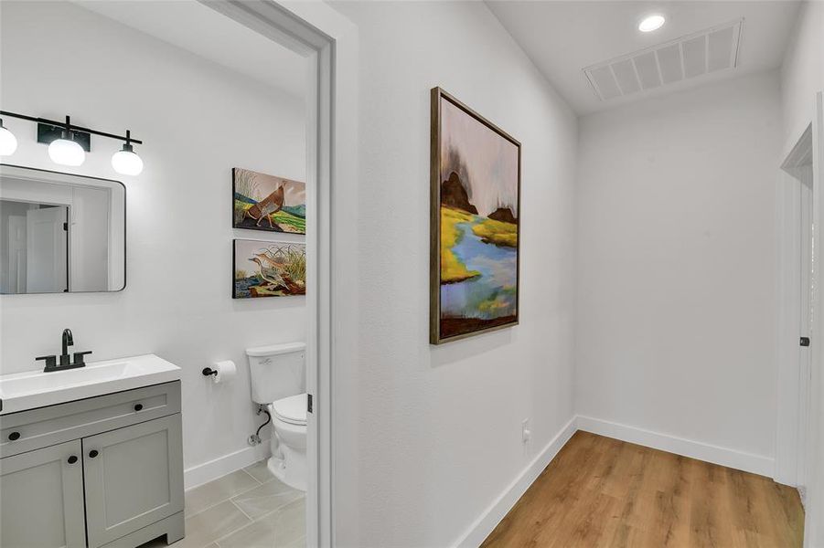 Full shared bathroom featuring tile and patterned flooring, enclosed tub / glass door shower combo, vanity, and toilet